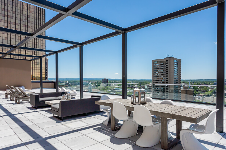 A rooftop deck with a table and chairs and a view of the city.