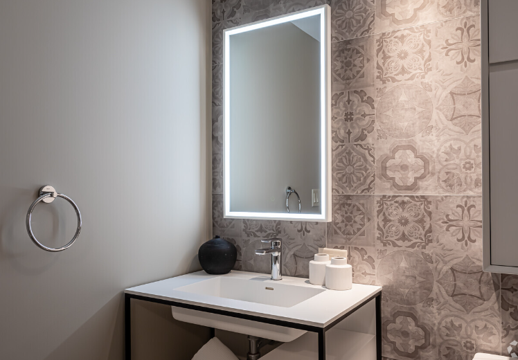 A bathroom with a sink , mirror and towel ring.