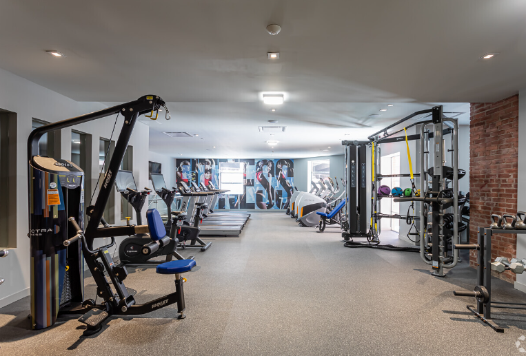 A large gym with a lot of equipment and a brick wall.