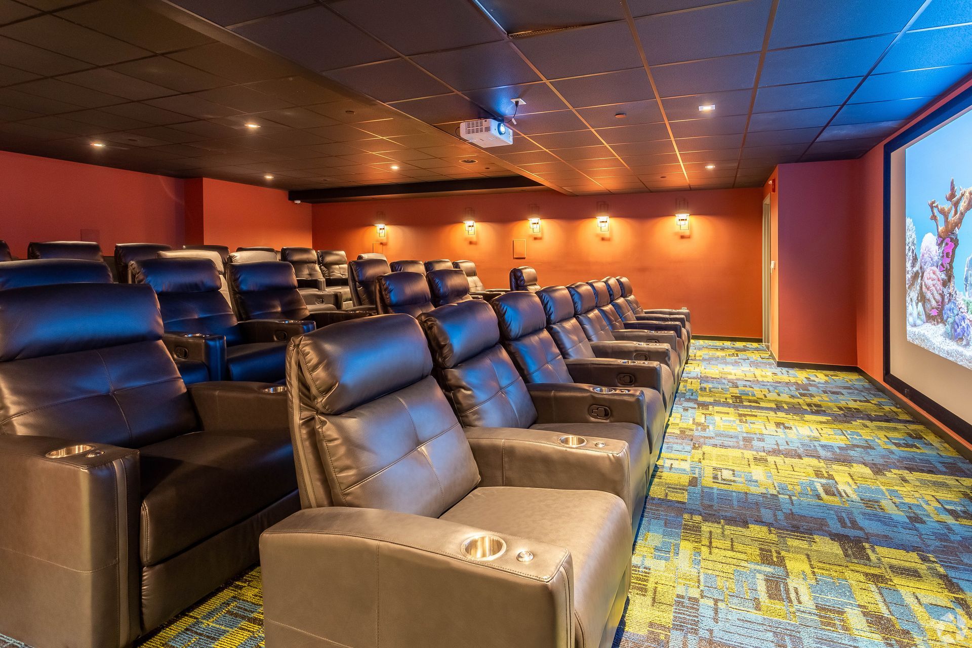A movie theater with lots of chairs and a projector screen.