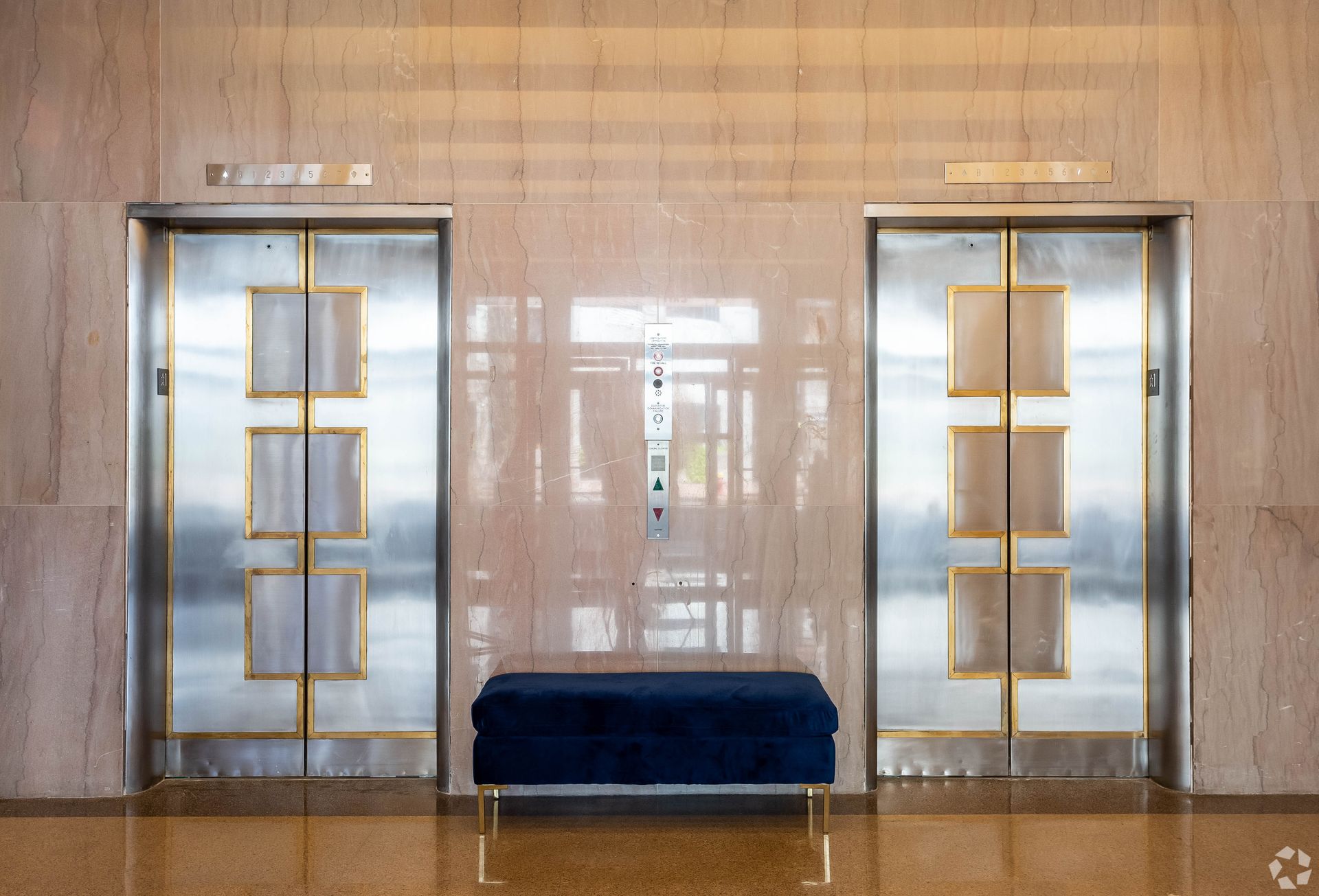 A blue bench is sitting in front of two elevators in a building.