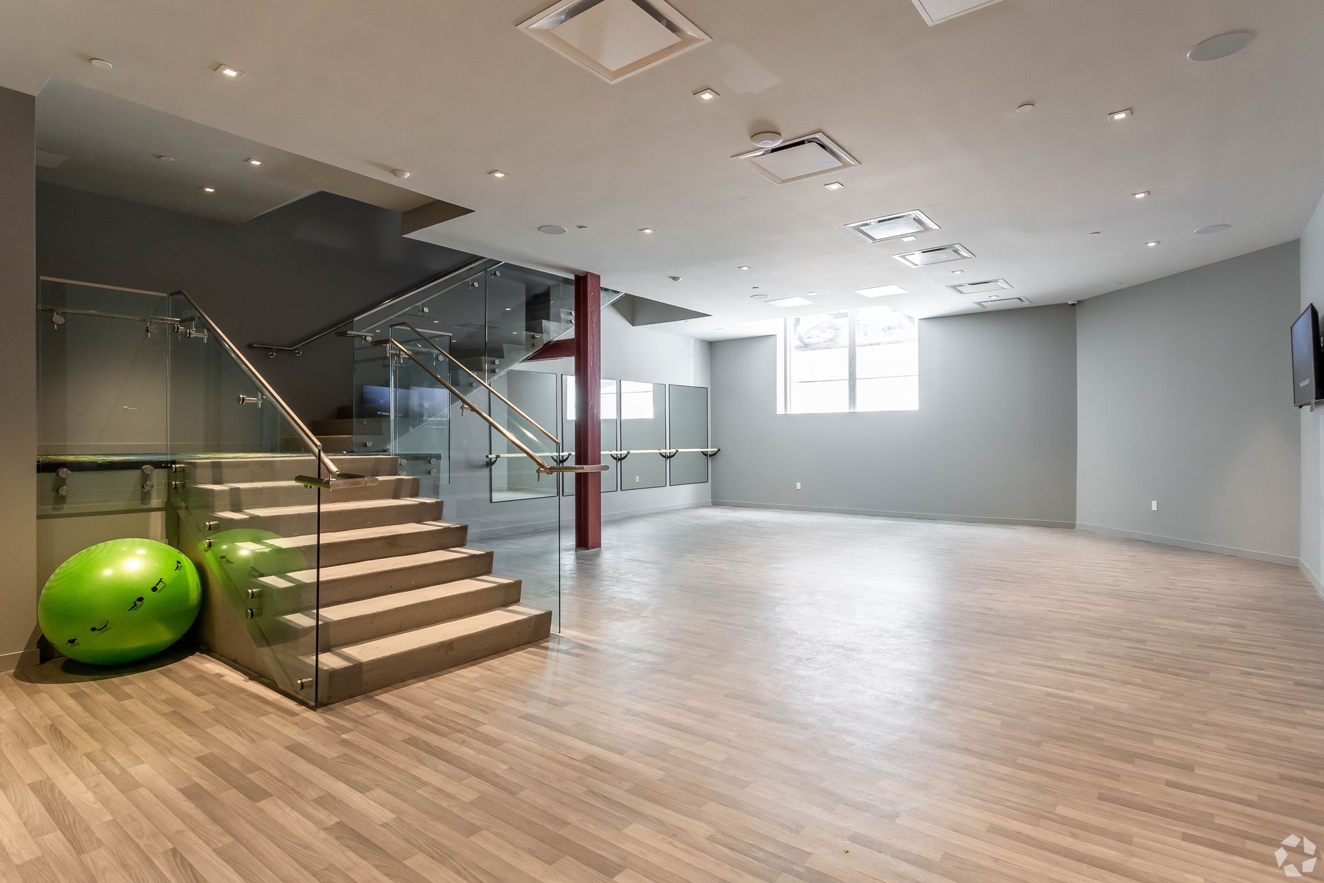 A large empty room with stairs and a green ball on the floor.