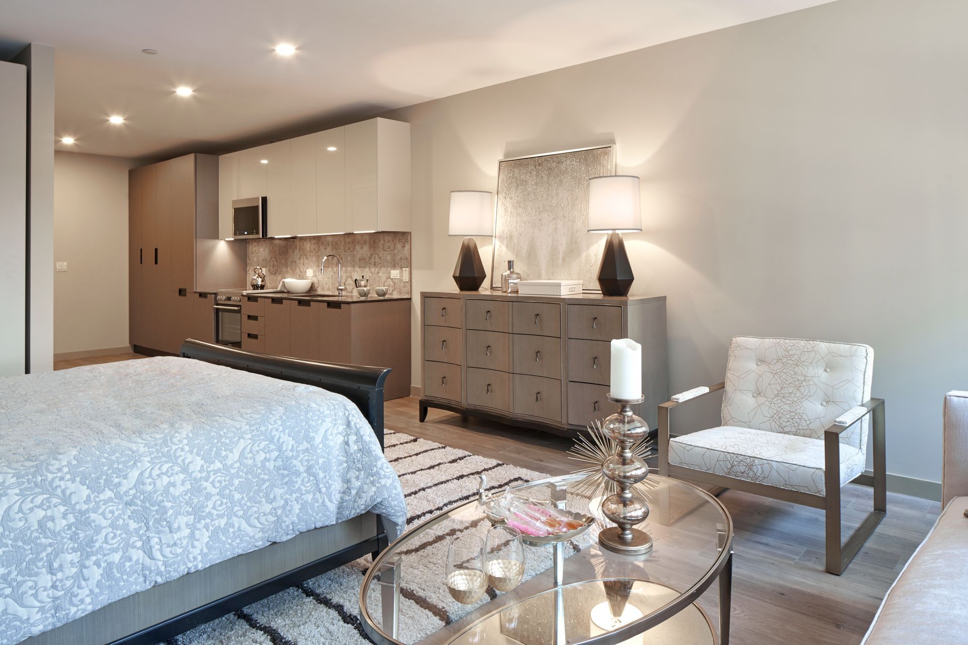 A bedroom with a bed , chair , coffee table and kitchen.