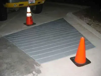 Concrete ramp with a gray, grooved surface. Two orange traffic cones mark the edges.