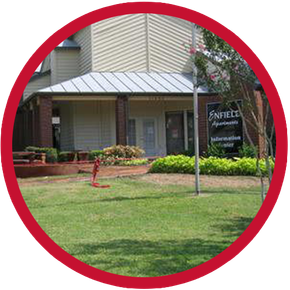 Exterior of Pine Hills Apartments office building, light beige with brick accents, surrounded by green lawn and landscaping. Exterior of Pine Hills Apartments office building, light beige with brick accents, surrounded by green lawn and landscaping.