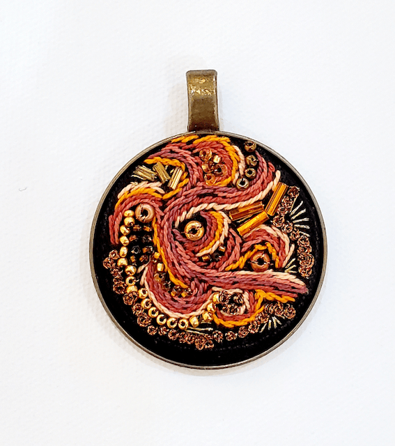 A pendant with a snake on it is on a white surface.