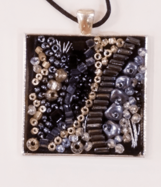 A square pendant with a lot of beads on it