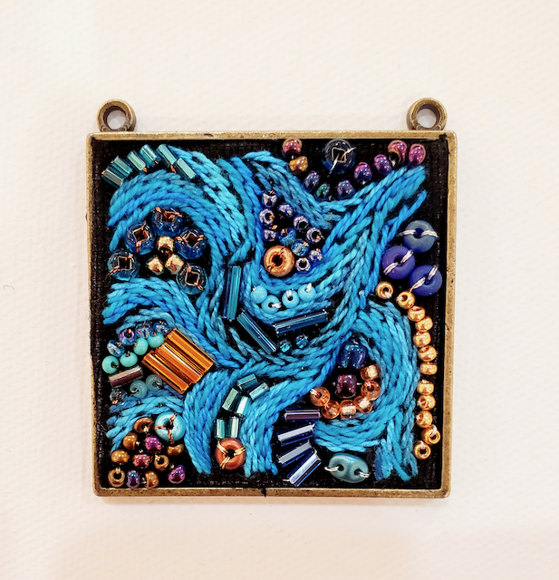 A square pendant with blue beads on it