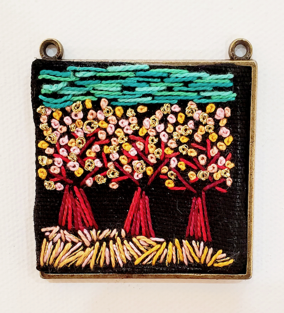 An embroidered picture of three trees with flowers on them