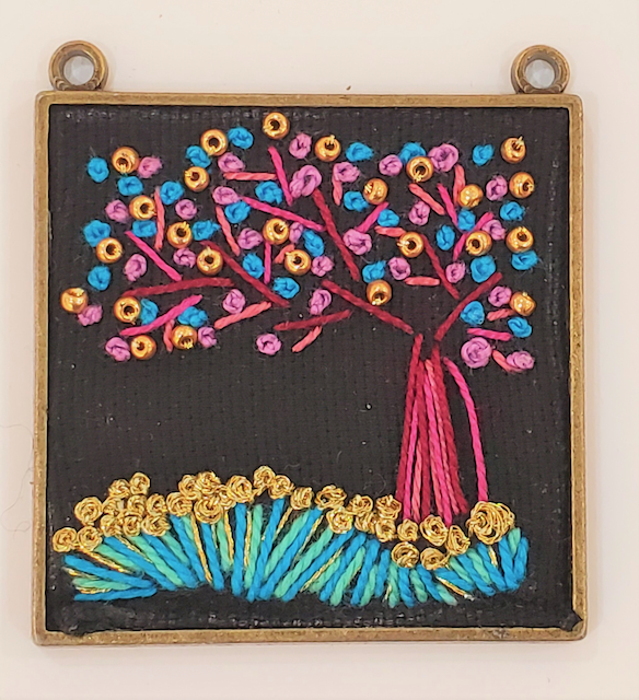 A picture of a tree with flowers embroidered on it
