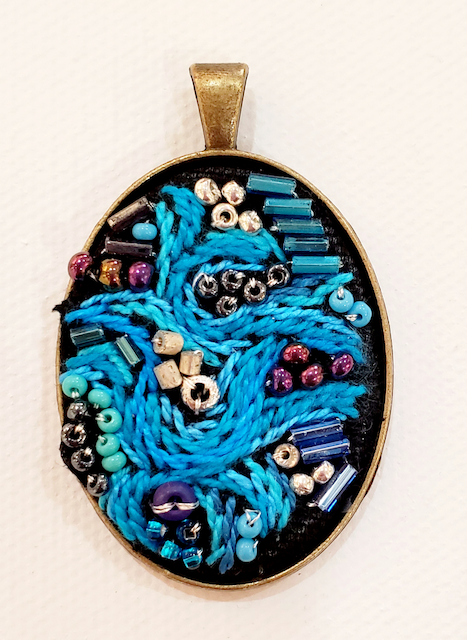 A pendant with blue beads on a black background