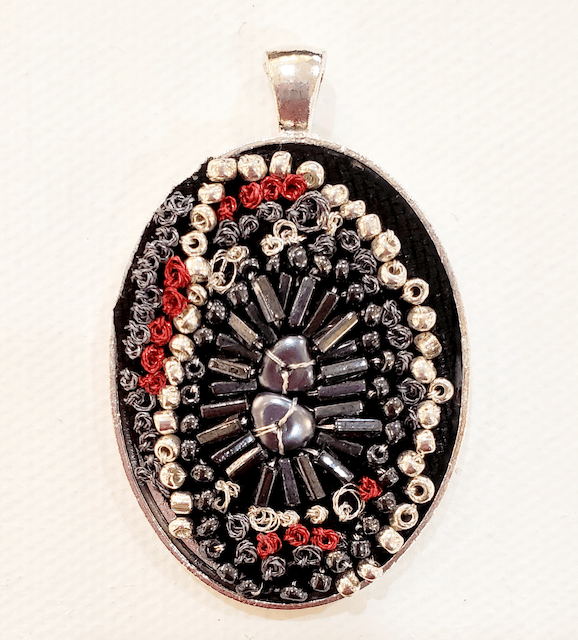 A black and silver pendant with red beads on it