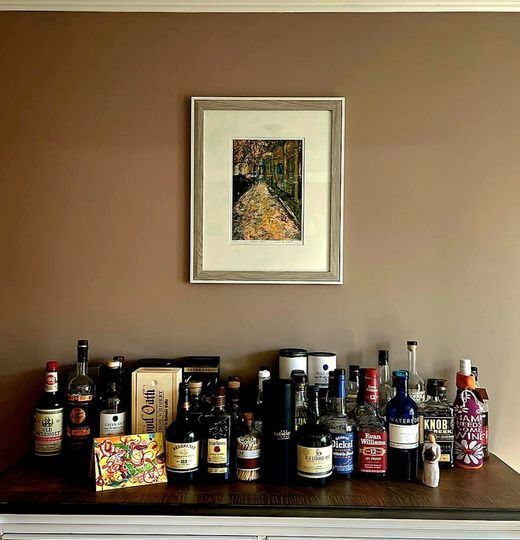 A table full of bottles and a picture on the wall above it