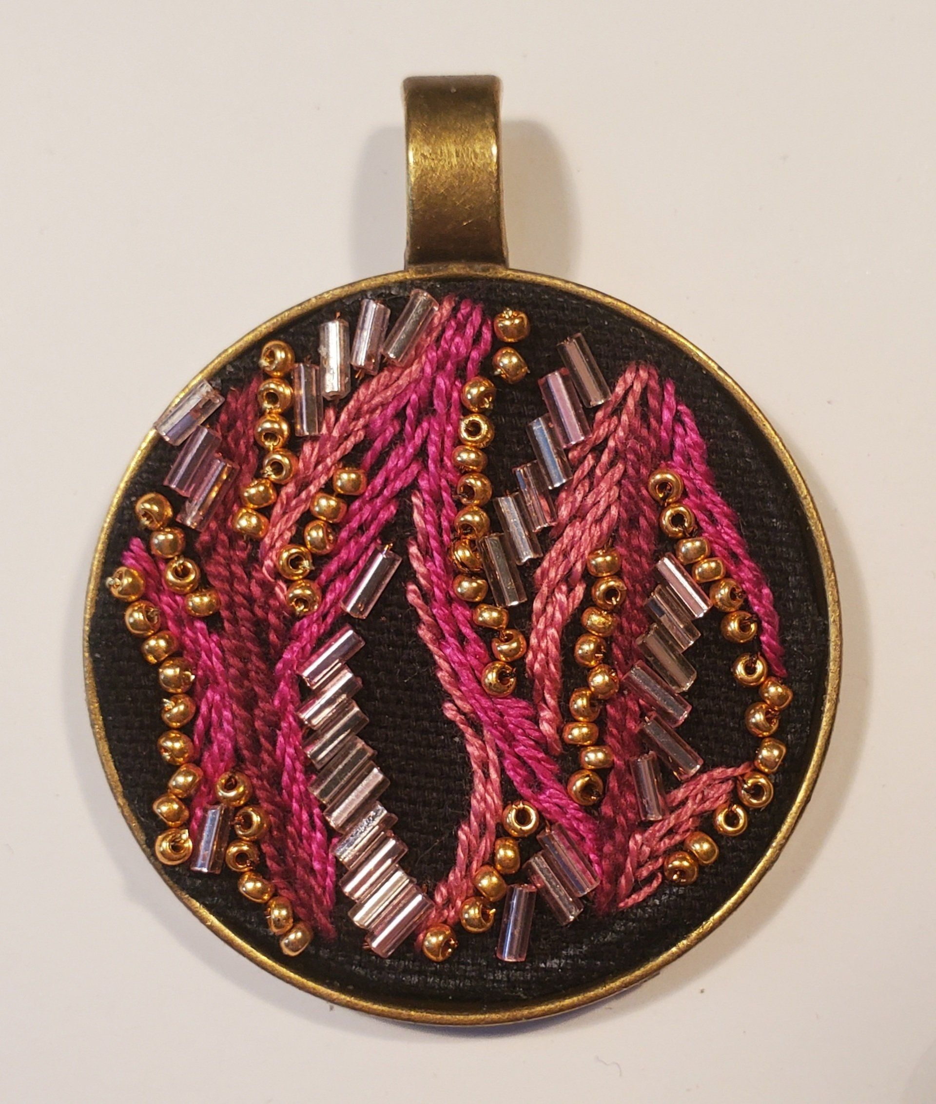 A round pendant with pink and silver beads on it