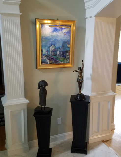 A painting is hanging on a wall above two statues