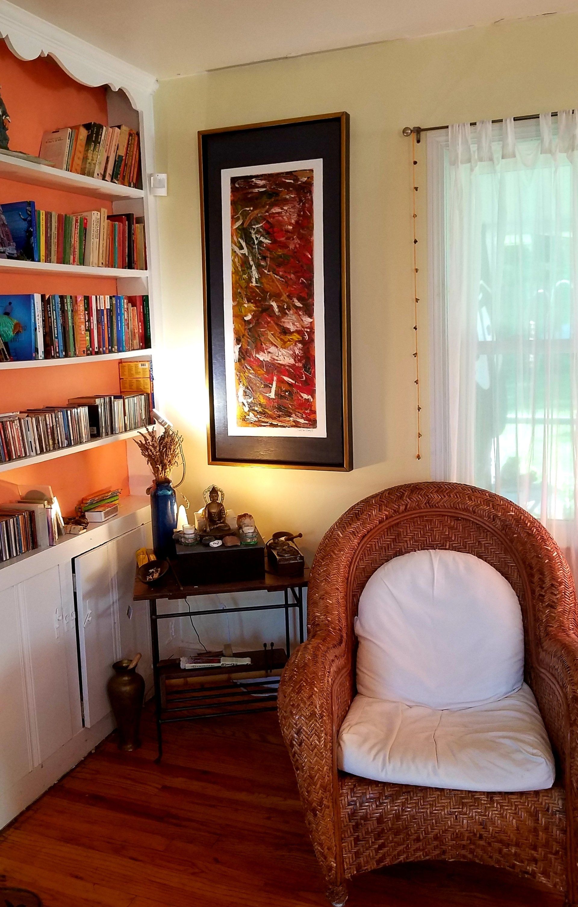 A living room with a wicker chair and a painting on the wall