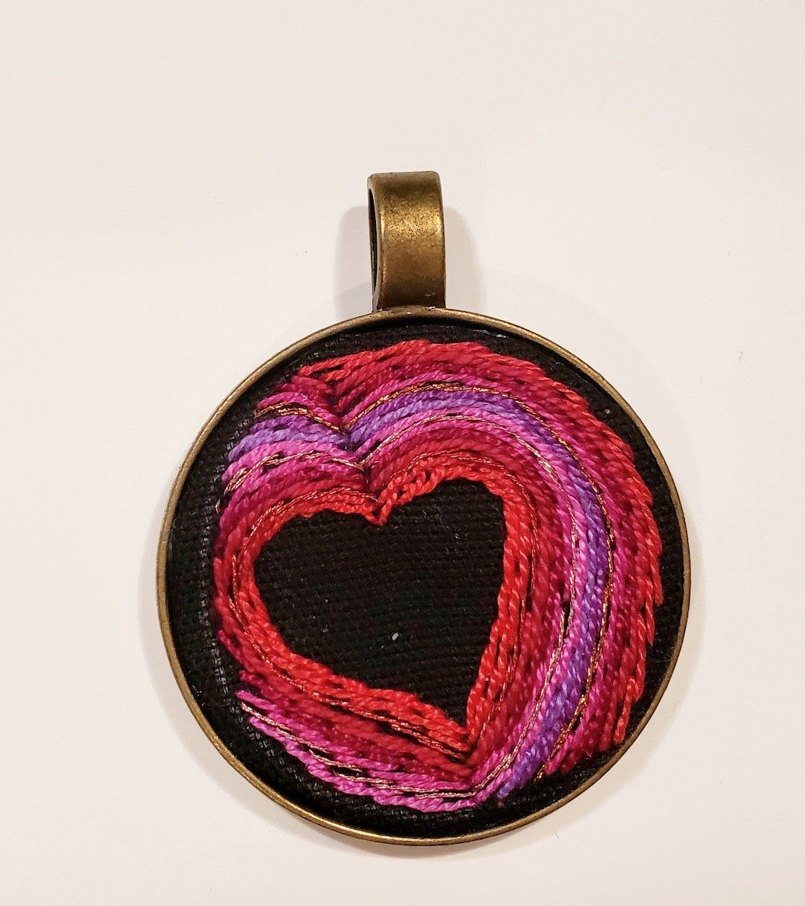 A round pendant with a red and purple heart on it