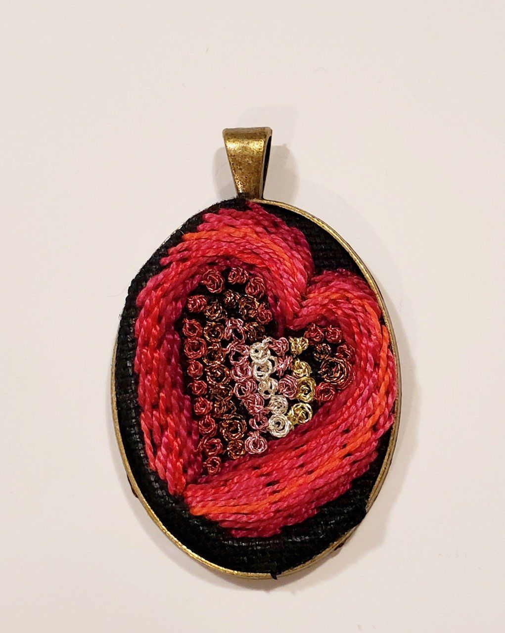 A pendant with a red heart embroidered on it