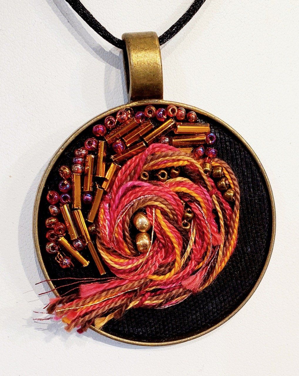 A pendant with beads and yarn on it