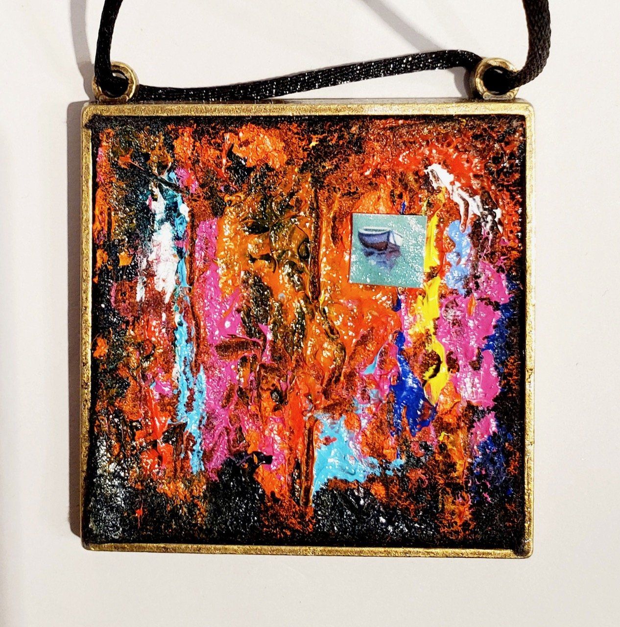 A necklace with a painting of a boat on it
