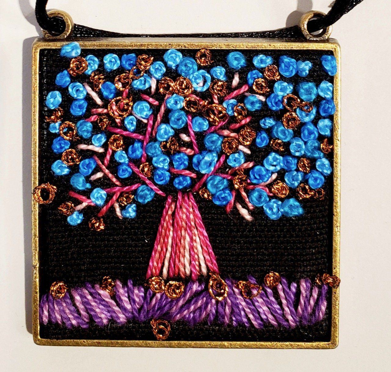 A necklace with a tree embroidered on it