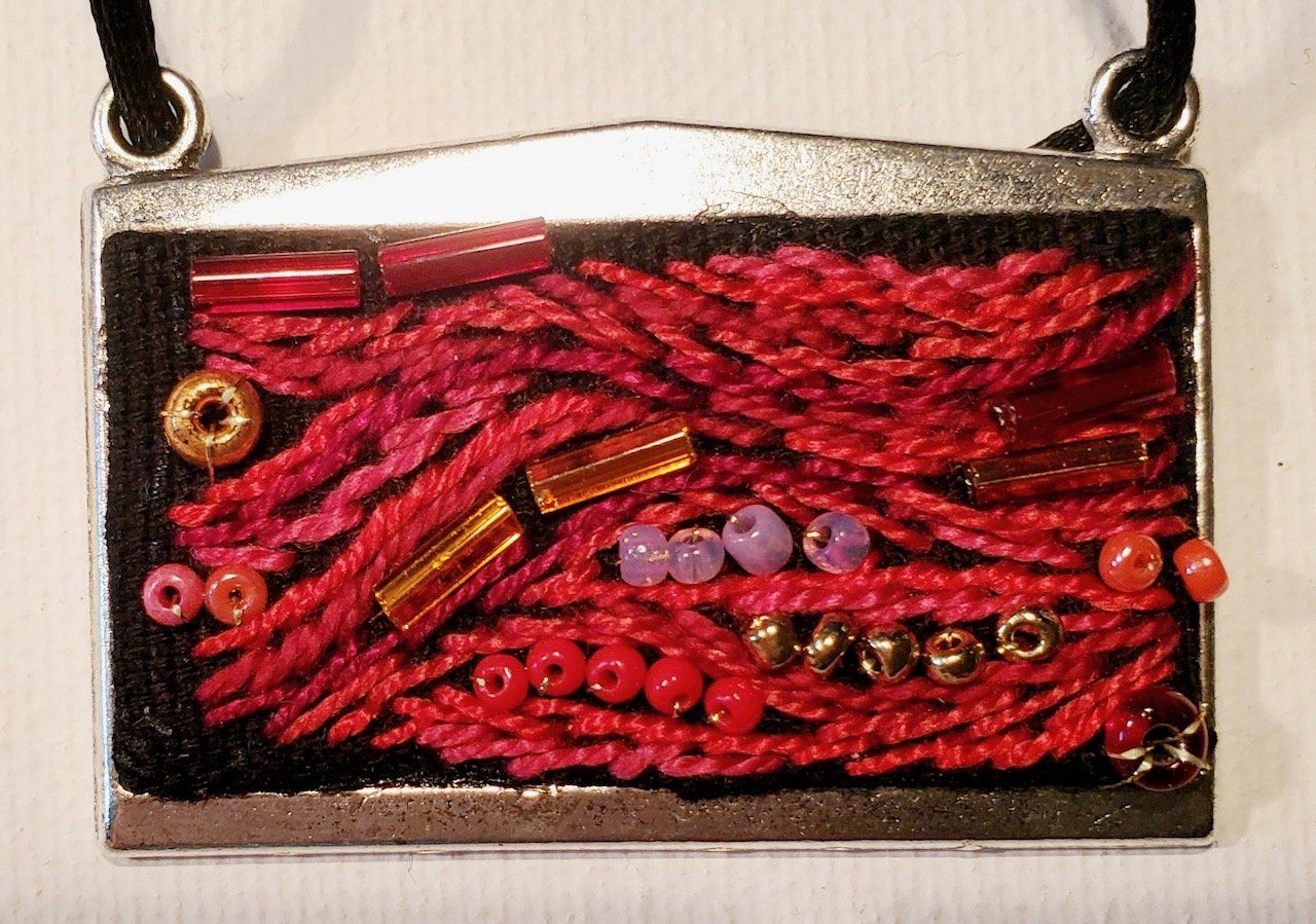 A silver pendant with red beads on it