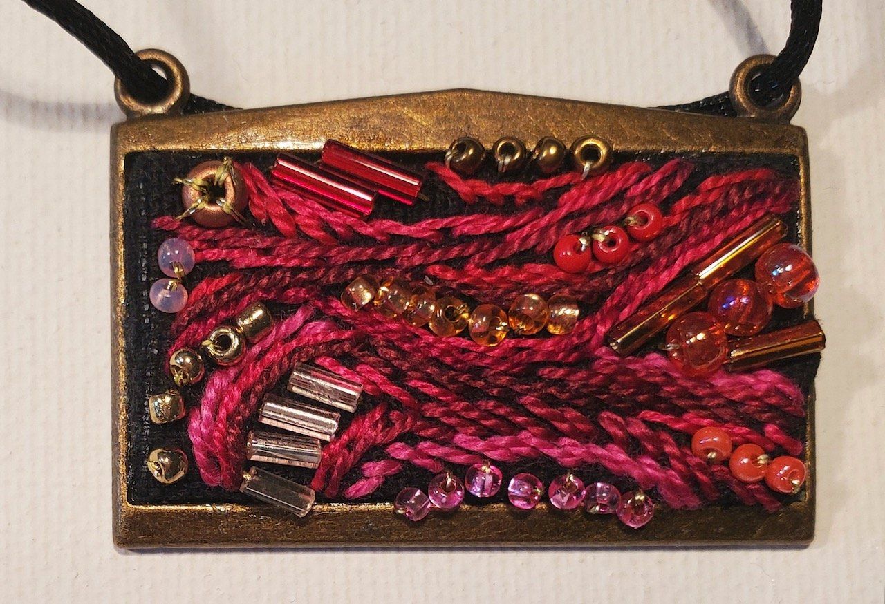 A necklace with pink beads and yarn on it