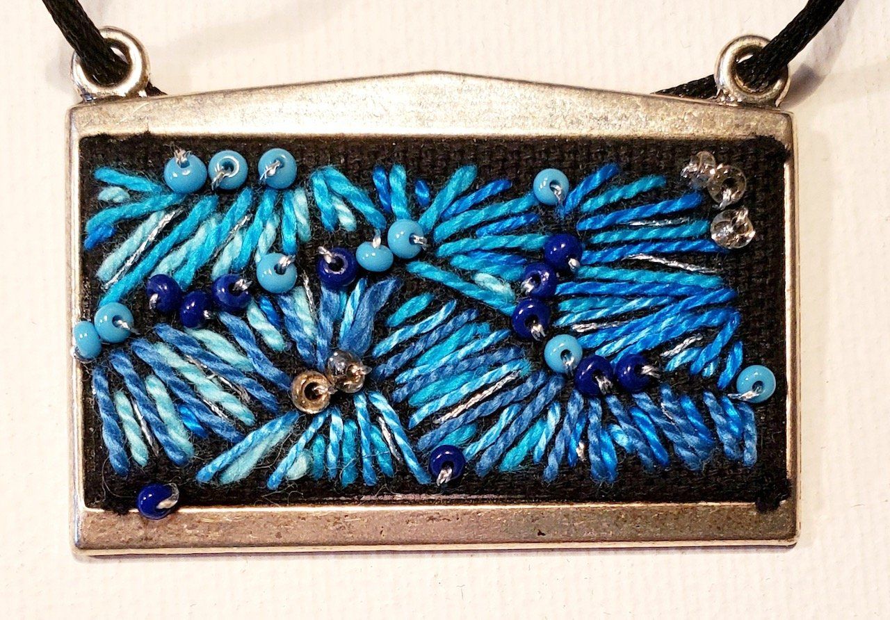 A silver pendant with blue beads on it