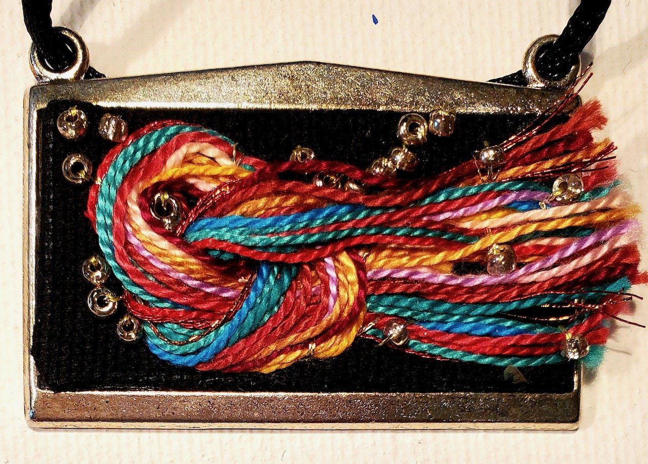 A necklace with colorful yarn and beads on it