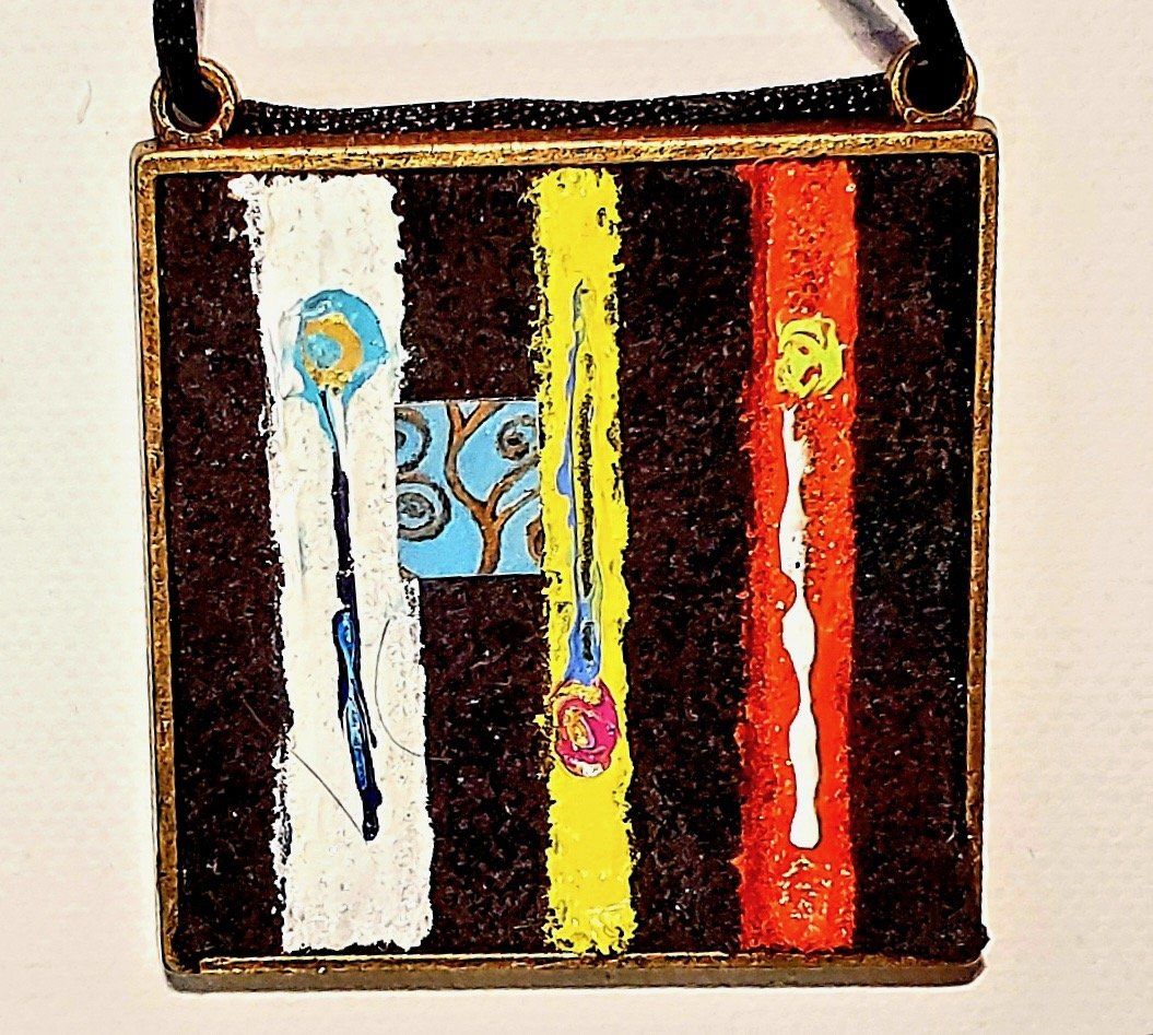 A necklace with a painting on it that says ' i ' on it