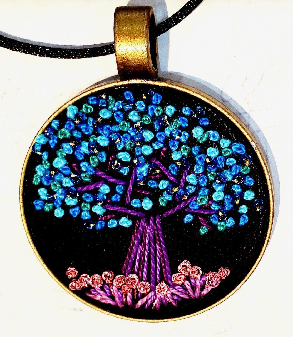 A pendant with a tree and flowers on it