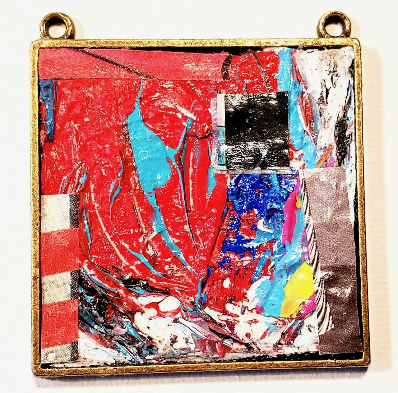 A square pendant with a colorful painting on it