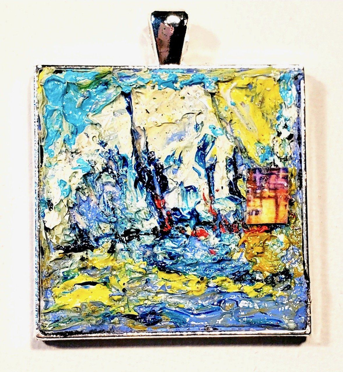 A pendant with a painting on it is hanging on a wall.