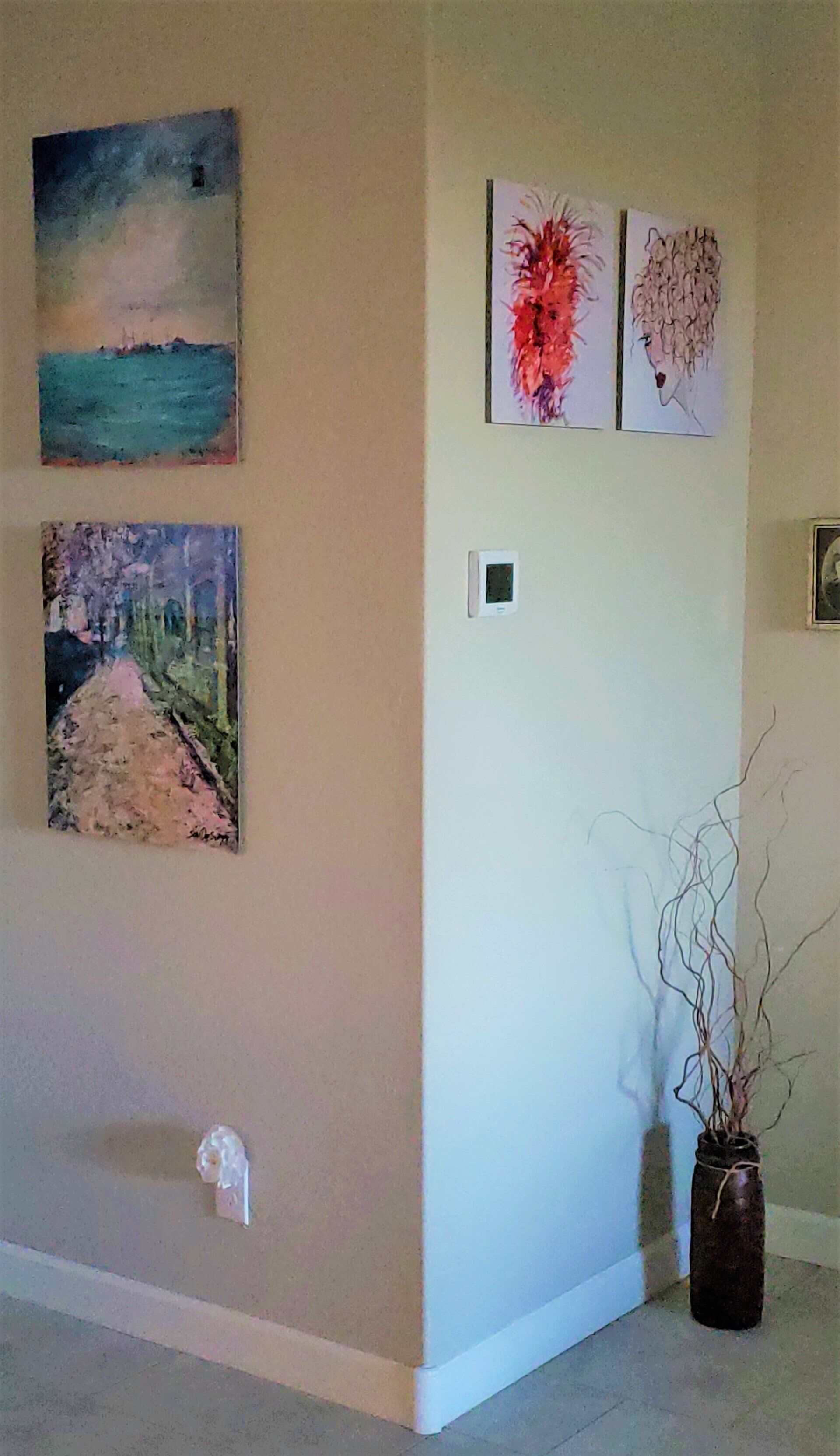 A living room with a vase and paintings on the wall.