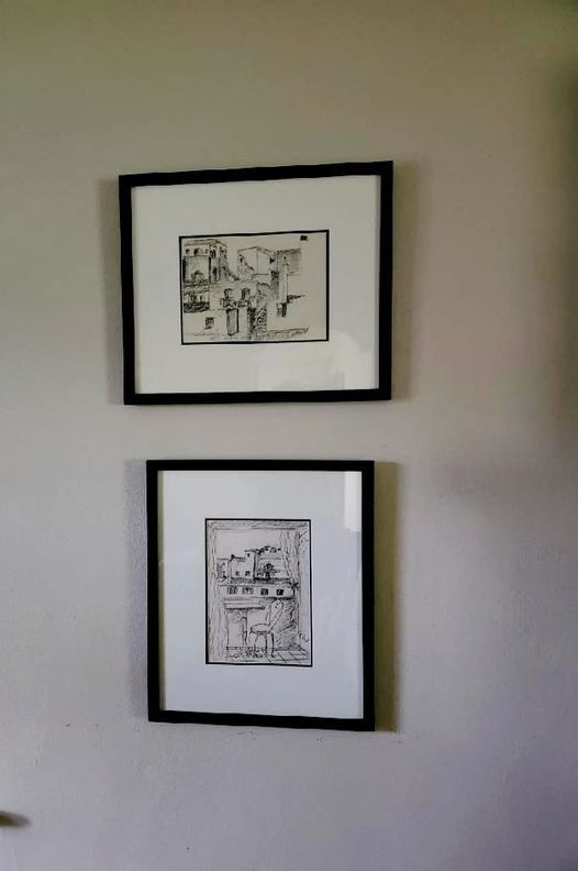 Two framed pictures are hanging on a wall.
