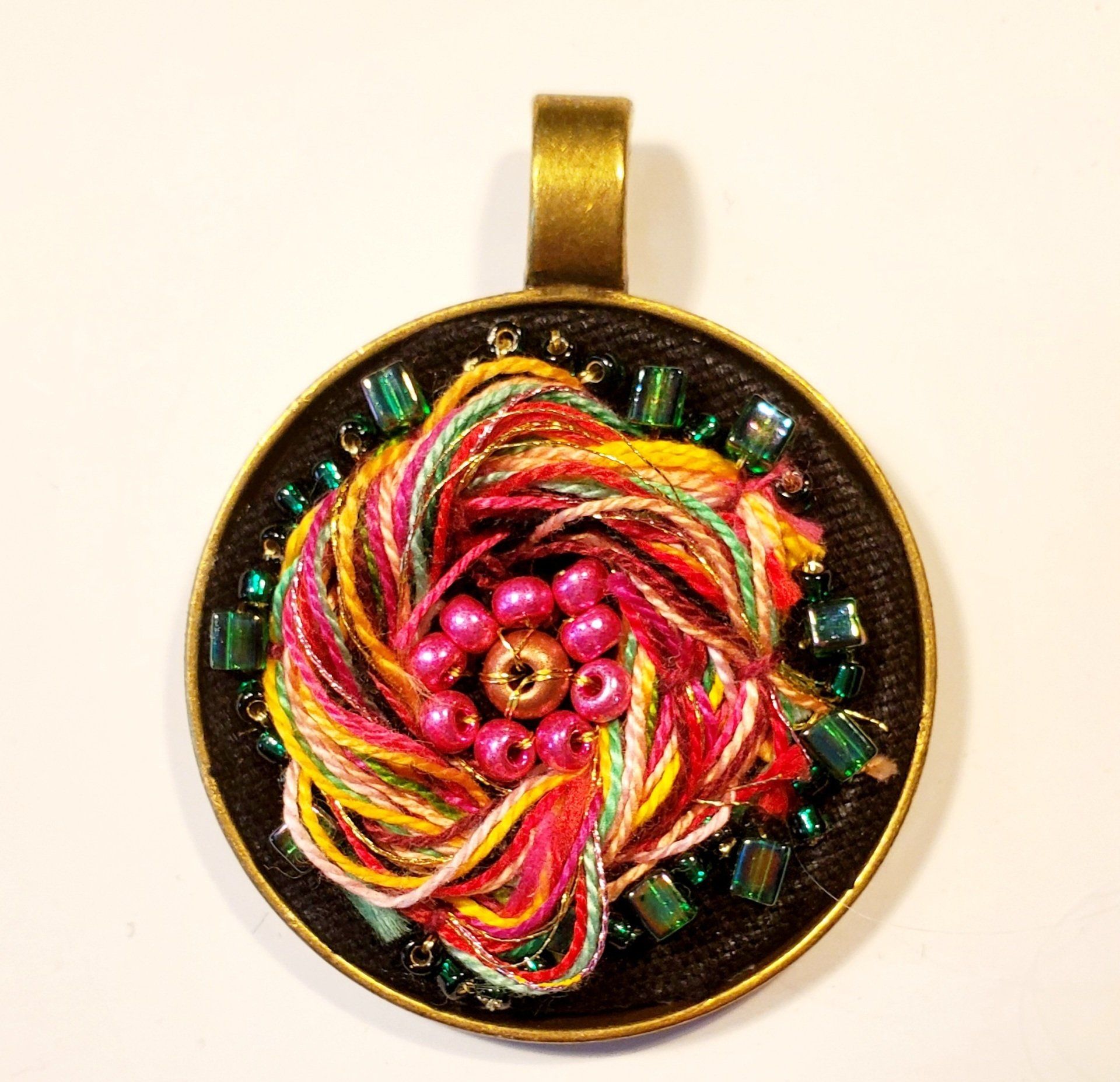 A round pendant with yarn and beads on it