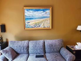 A living room with a couch and a painting on the wall.