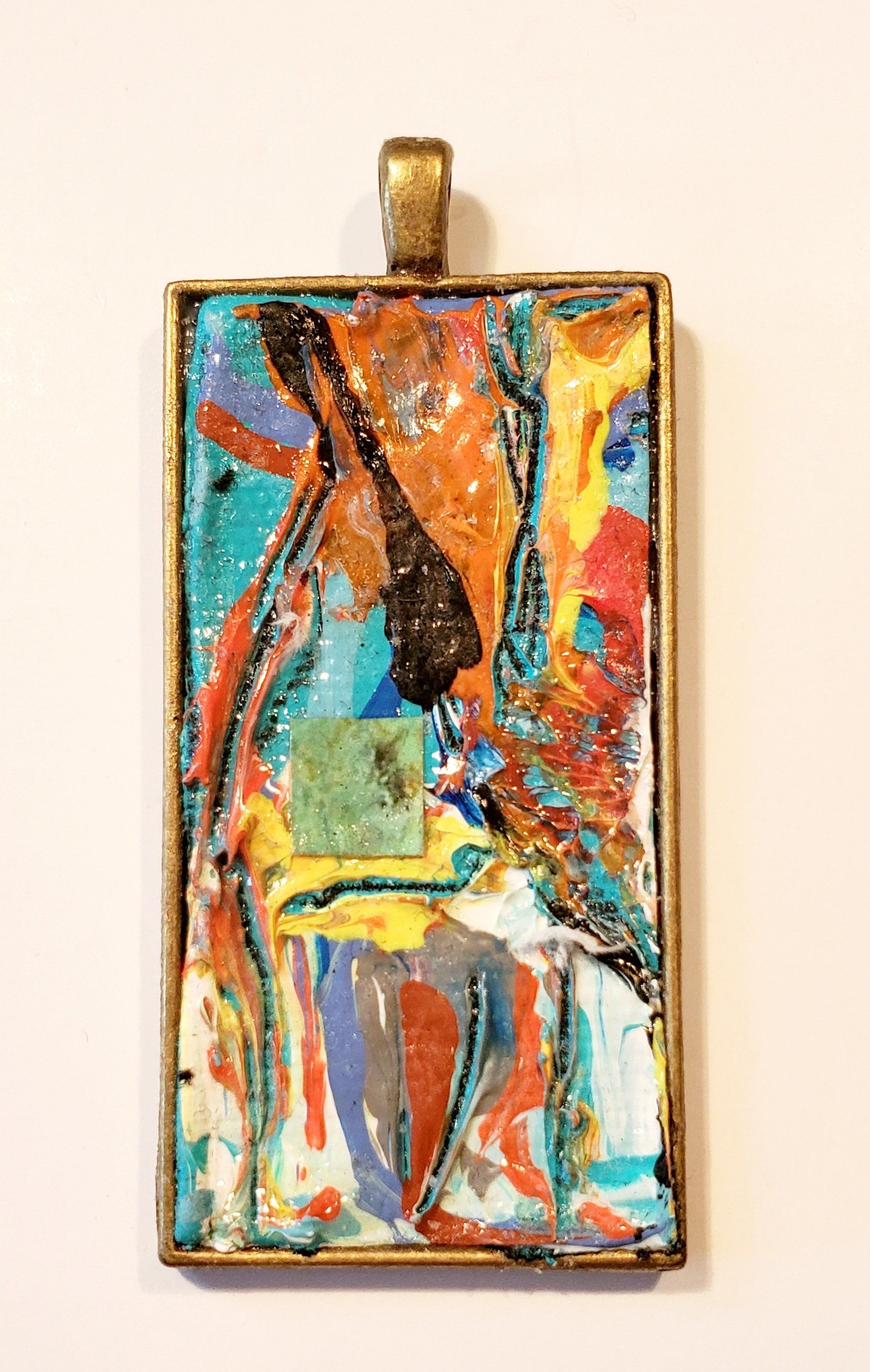 A pendant with a painting on it is hanging on a wall.