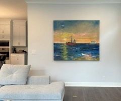 A living room with a couch and a painting on the wall.