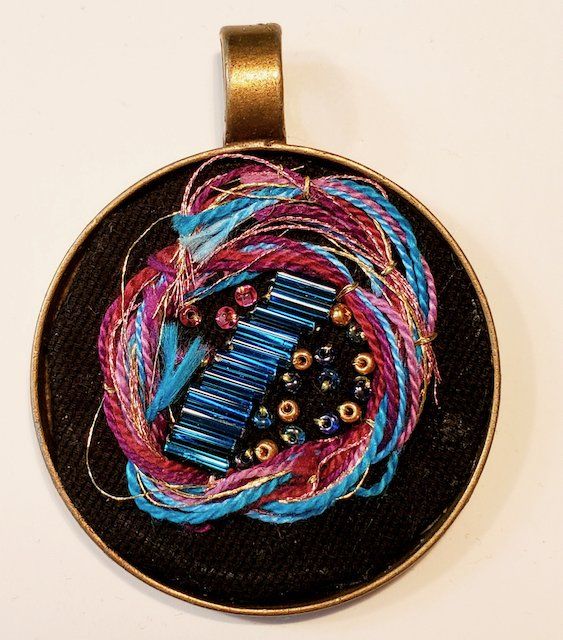A pendant with blue and pink beads on a black background