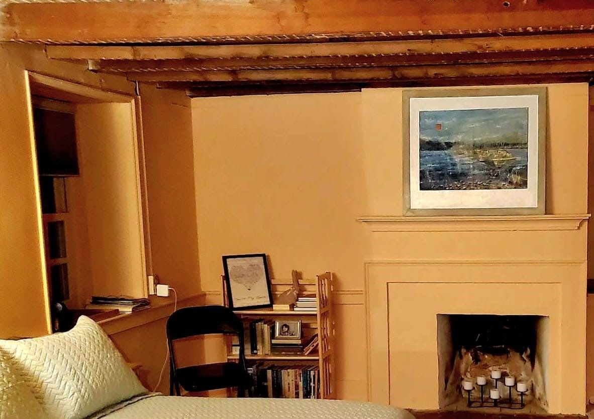 A bedroom with a fireplace and a painting on the wall