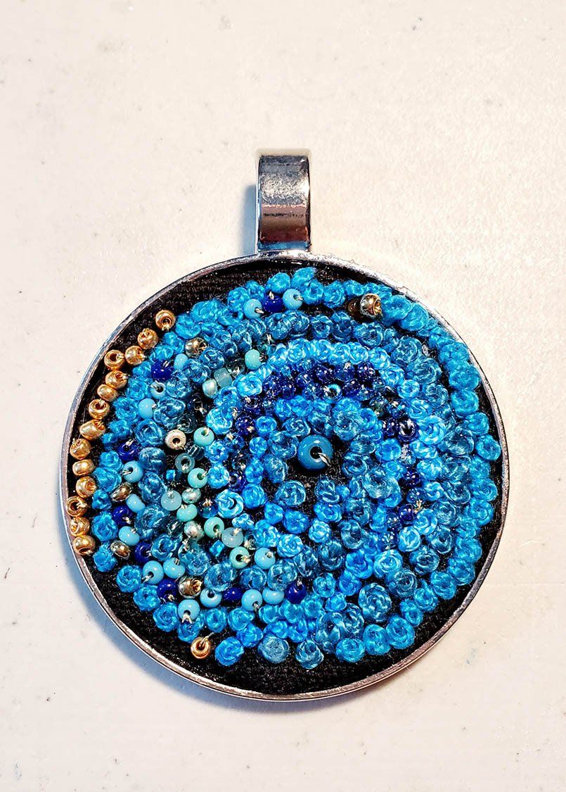 A pendant with blue beads on a white surface