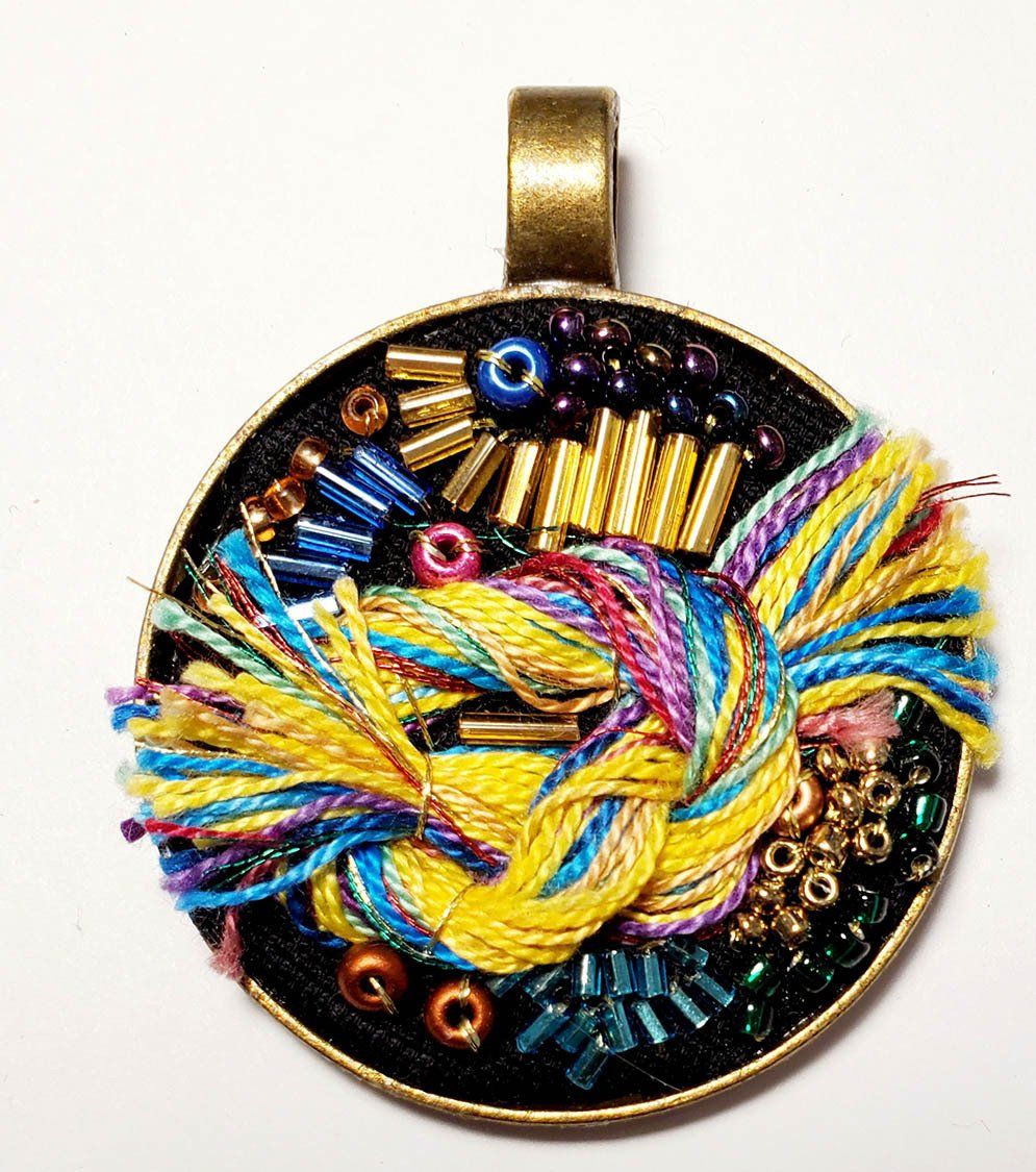 A pendant with yarn and beads on it
