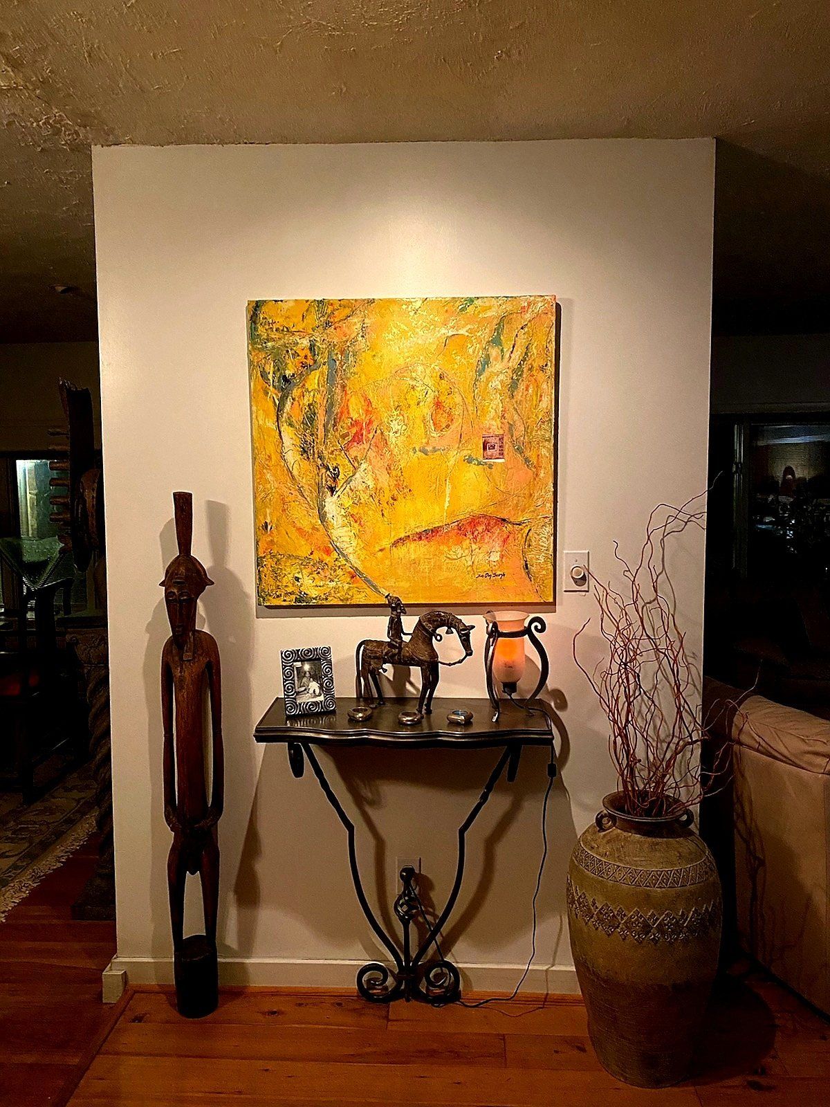 A painting is hanging on a wall above a table in a living room.