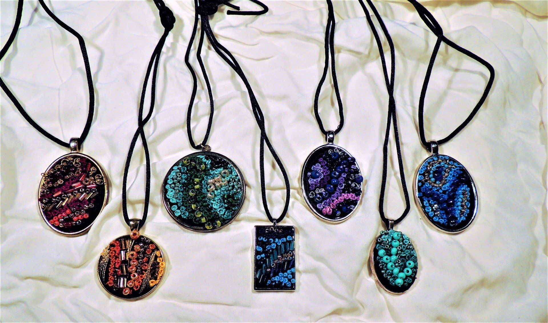 A group of necklaces are sitting on a white cloth