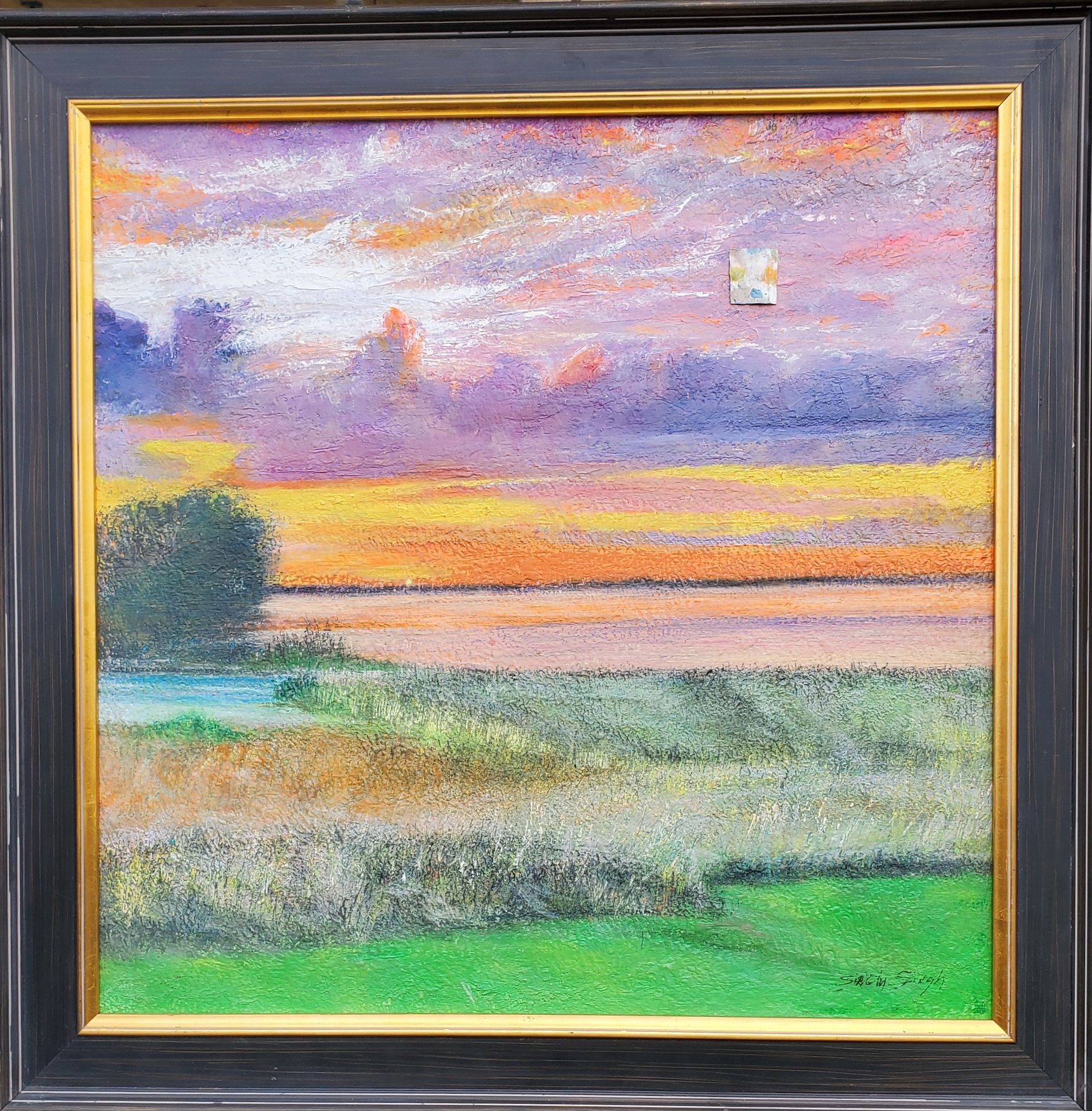 A framed painting of a sunset over a field