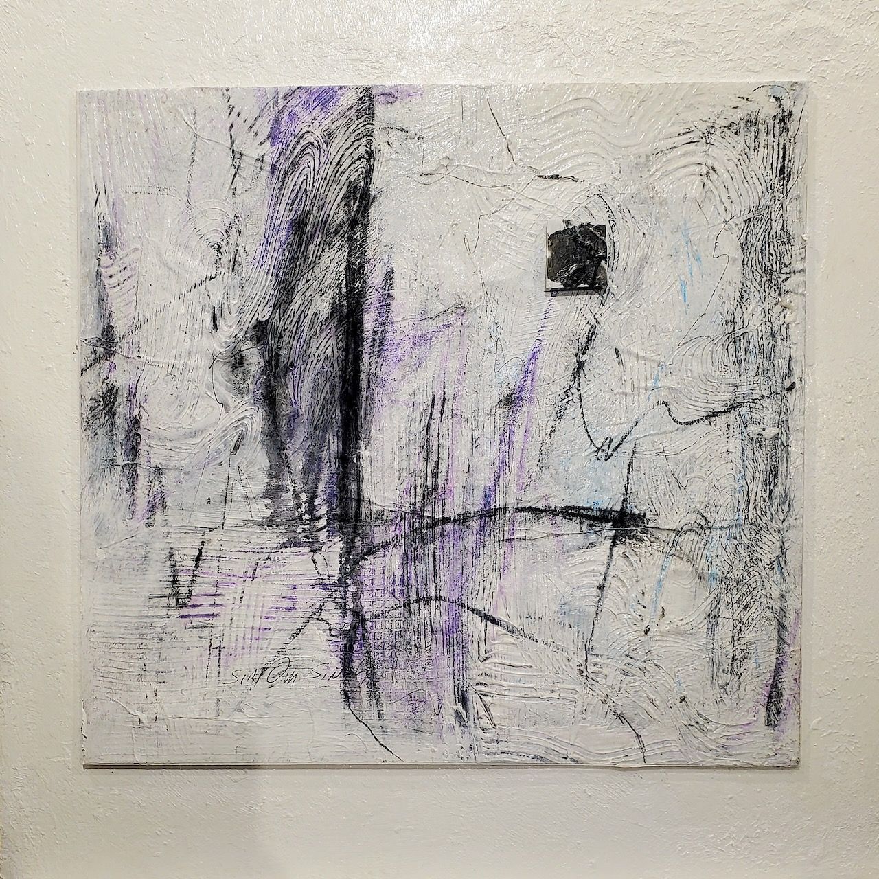 A white and purple painting is hanging on a white wall.