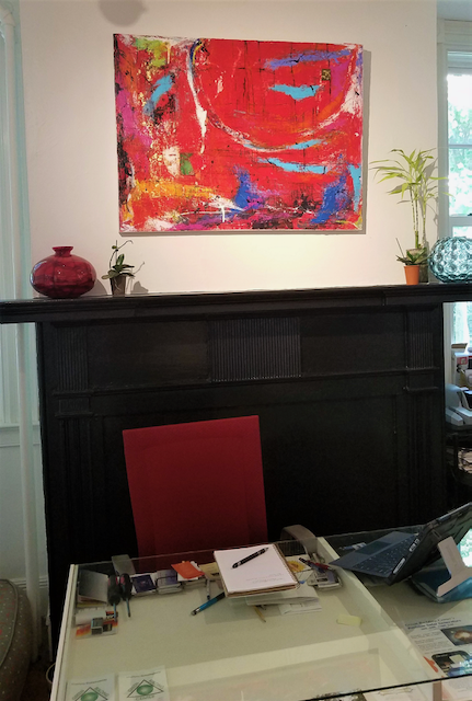 A living room with a fireplace and a painting on the wall