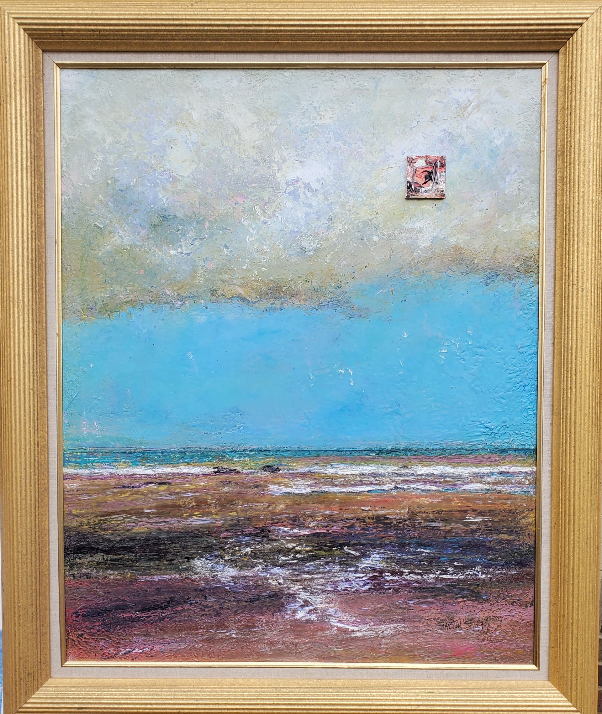 A painting of a beach with a blue sky in a gold frame.