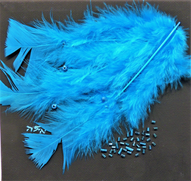 A bunch of blue feathers and beads on a black surface